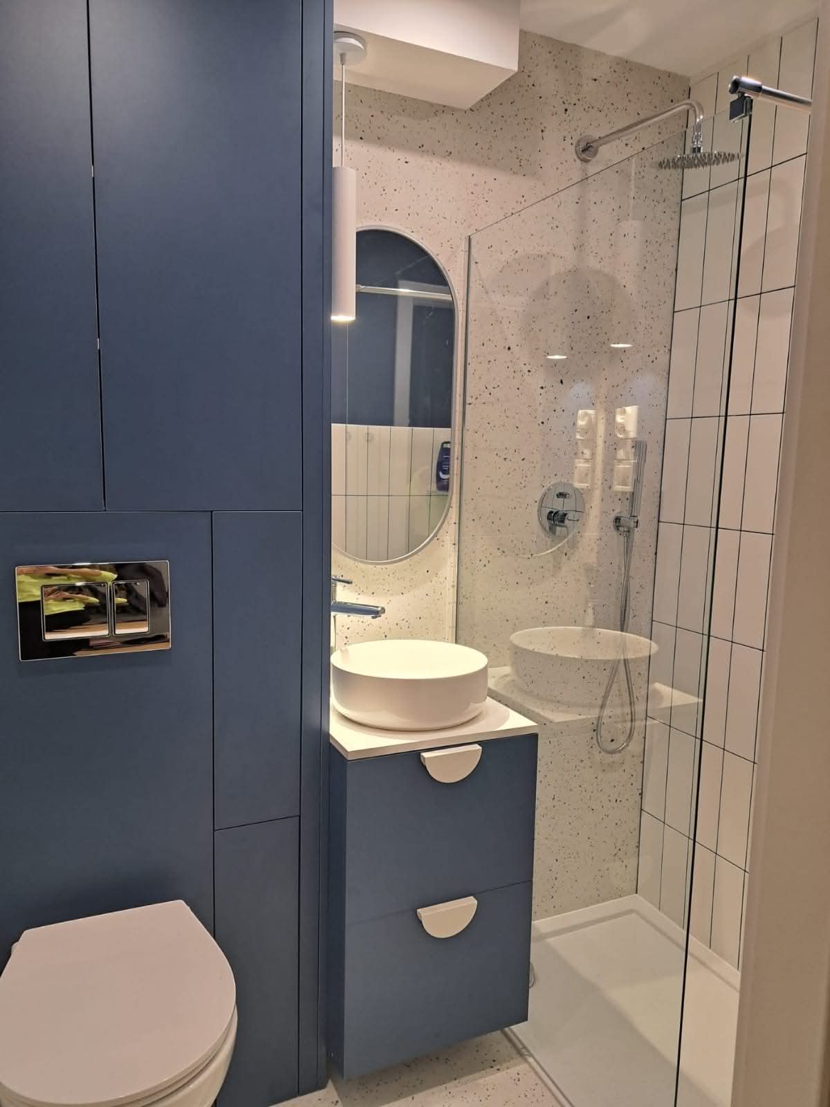 Contemporary blue bathroom with terrazzo tiles and round mirror